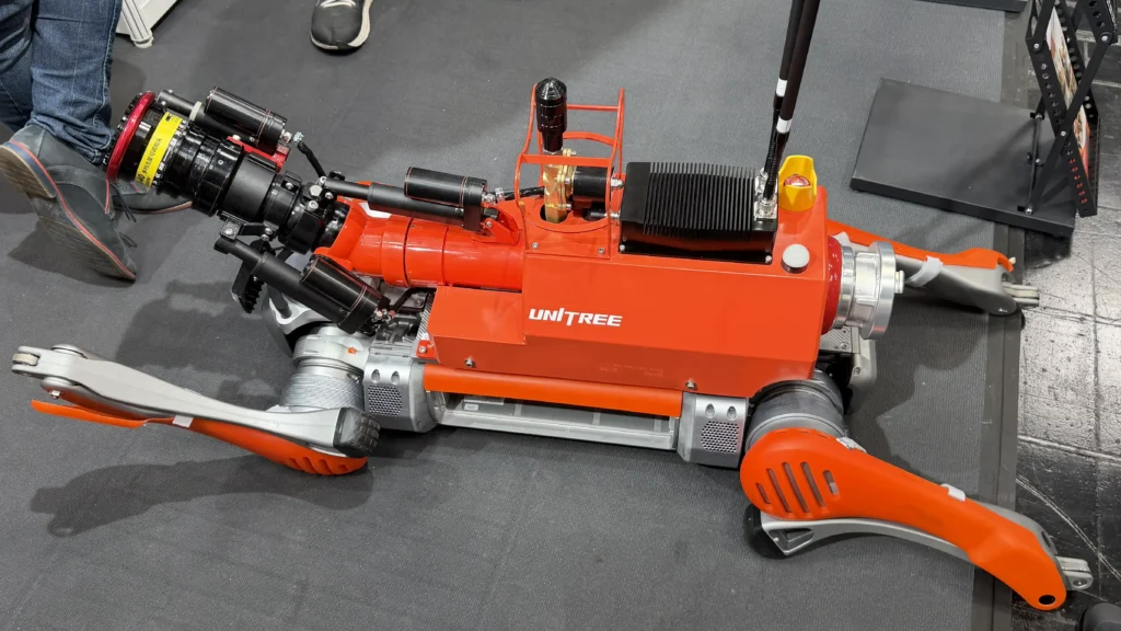 Red Uni-TREE industrial machine with black components and orange accents, placed on a dark workshop floor, with a worker's shoe visible nearby.